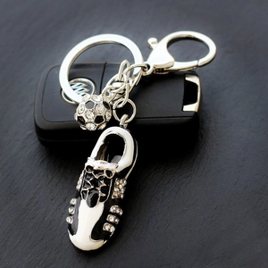 Sparkling soccer shoe and ball keychain with rhinestones on a black car key