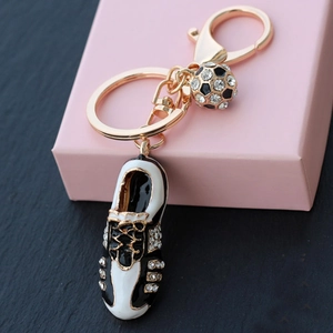 Custom gold football boot keychain with rhinestones and a crystal ball charm on stone background