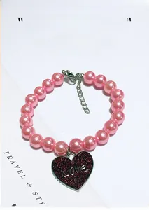 Detail of pink pearl cat collar with a red heart charm engraved with the word Love