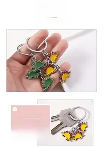 Detail shot of cute yellow and green dinosaur keychains featuring vibrant enamel stegosaurus