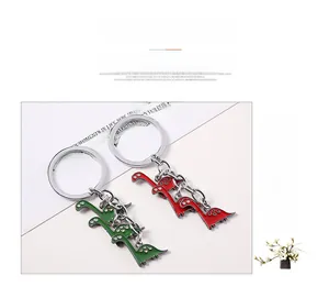 Close-up of green and red cartoon enamel dinosaur keychains with silver metal rings
