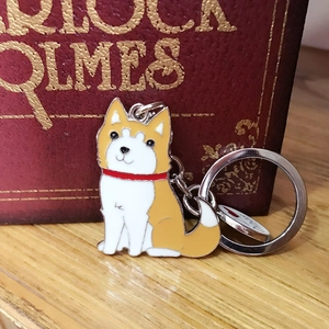 Détail d'un porte-clés en métal husky dessin animé avec finition en émail orange vif
