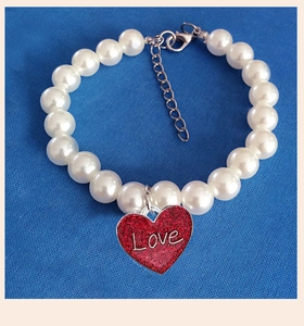 Detailed view of beaded pet collar with red glitter heart pendant and Love engraving