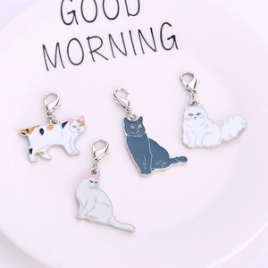 Set of four colorful enamel cat keychains with lobster clasps on a white ceramic plate