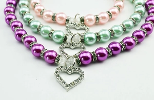 Detail of colorful pet pearl collars with heart-shaped rhinestone pendants in three shades