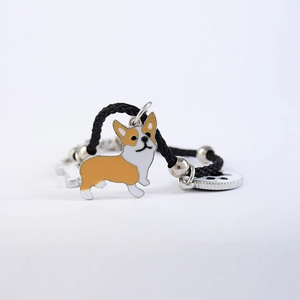 Detail van een geweven armband met een Corgi-hondenhanger en metalen kralen op zwart koord