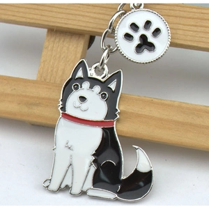 Gros plan du porte-clés husky en émail avec breloque patte sur fond de bois