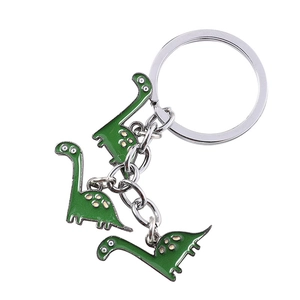 Cute green cartoon dinosaur keychain with silver metal ring and three pendants on white background