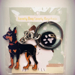 Détail du porte-clés émaillé Doberman avec breloque patte dans son emballage d'origine