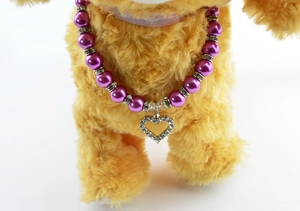 Close-up of purple faux pearl pet necklace featuring a sparkling diamond heart pendant