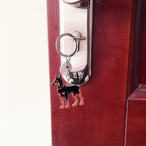 Gros plan détaillé d'un porte-clés Doberman en émail suspendu à une clé dans une serrure