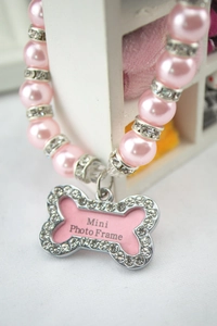 Macro shot of pink pearl pet collar with rhinestone bone-shaped photo frame pendant