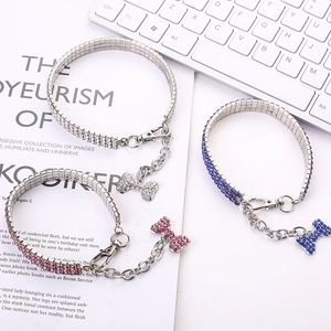 Close-up of three-row rhinestone pet collar with sparkling bone pendant and metal chain