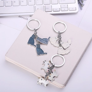 Detailed view of metal cat keychains in three colors on a desk with a white keyboard