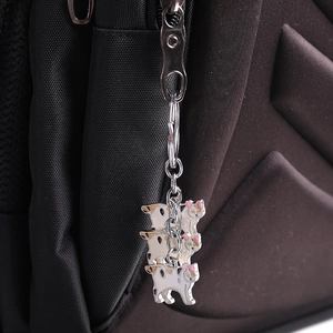 Three-in-one calico cat enamel metal keychain accessory hanging on a black backpack