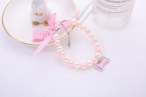 Pink and white pearl pet necklace with checkered bow and rhinestone bone pendant detail