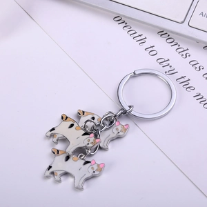 Detailed close-up of metal keychain with four calico cat enamel charms on white desk