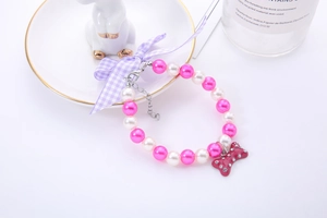 Detail of pink and white pearl pet necklace with purple bow and crystal bone charm
