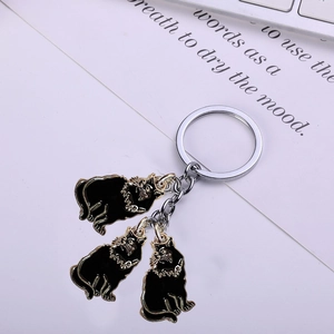 Close-up of black enamel cat pendants on gold-plated keyring with metal chain detail
