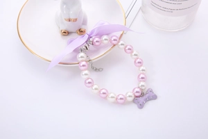 Detail of pink pearl pet necklace with purple bow and rhinestone bone pendant