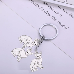 Detailed close-up of three white enamel Sphynx cat charms on a silver metal keychain