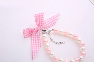 Detail of pink and white faux pearl pet necklace with a plaid bow and metal clasp