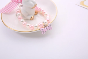 Detail of pink and white pearl pet necklace with a sparkling rhinestone bone charm