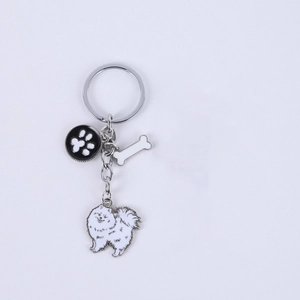 Detail of metal dog keychain featuring white Pomeranian, bone, and paw print pendants