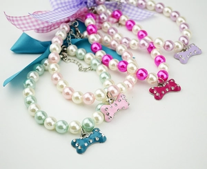 Detailed view of pearl pet collars with bone pendants and adjustable metal extension chains