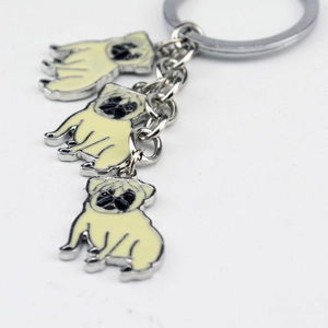 Macro detail of three enamel Pug charms on a silver zinc alloy keychain with chain links