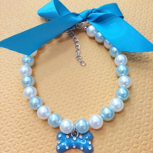 Detail of pet pearl necklace with blue satin bow and rhinestone bone pendant