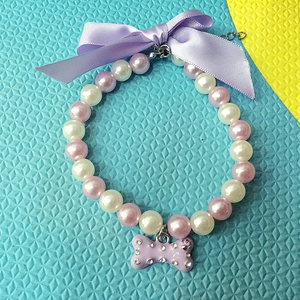 Detail of purple pearl pet collar with a rhinestone bone pendant and satin bow tie