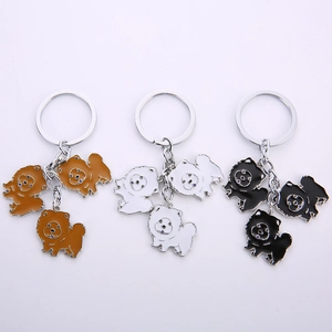 Detailed view of three enamel dog keychains in brown, white, and black with silver rings