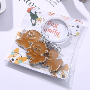 Close-up of three brown enamel dog charms on a silver keychain with Dog Family packaging