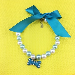 Detail of blue bow pearl pet necklace with a rhinestone-studded bone charm and metal chain