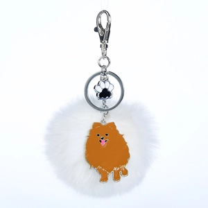 Détail d'un porte-clés pompon blanc en fausse fourrure avec pendentif chien Loulou de Poméranie