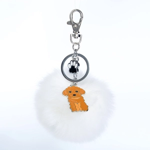 Détail d'un porte-clés pompon blanc avec pendentif patte de chat et fermoir mousqueton
