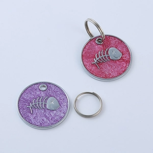 Detail view of round glitter pet ID tags featuring fishbone charms in pink and purple colors