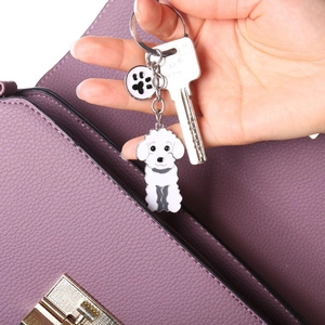 Détail d'un porte-clés caniche dessin animé avec patte sur un sac à main violet