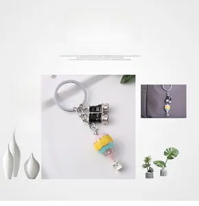 Detailansicht eines Heißluftballon-Schlüsselanhängers, der an einer grauen Handtasche hängt