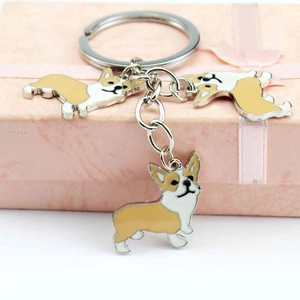 Detailed view of three metal Corgi charms on a keyring placed over a pink gift box