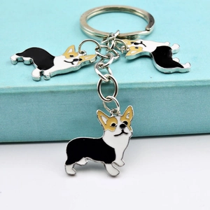 Detail of metal Corgi keychain with oil-drop craftsmanship and triple charms on blue box