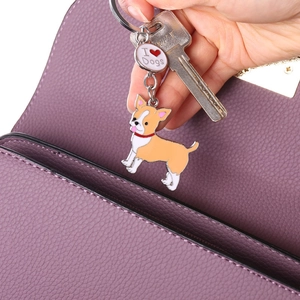 Hand holding enamel dog keychain with I Love Dogs pendant on a purple leather bag