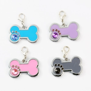 Detail of four colorful bone-shaped pet ID tags with rhinestone paw prints and lobster clasps
