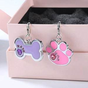 Detail of purple bone and pink paw pet ID tags with rhinestones on a jewelry box