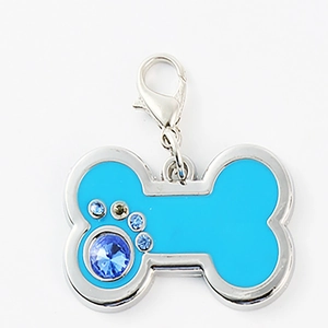 Macro detail of blue bone-shaped pet tag with rhinestone paw print and lobster clasp