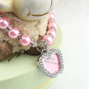 Detail eines rosa Perlenhalsbands mit diamantbesetztem Herz-Fotoanhänger für Haustiere
