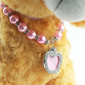 Makroaufnahme einer rosa Perlen-Tierhalskette mit herzförmigem Strass-Fotoanhänger