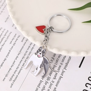 Detailed close-up of a bulldog enamel keychain with red heart charm on white porcelain