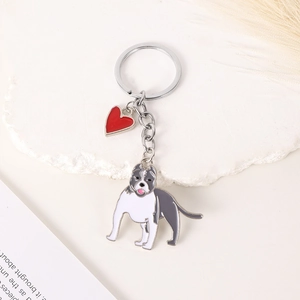 Close-up of silver metal bulldog keychain with a small red heart charm on white stone base